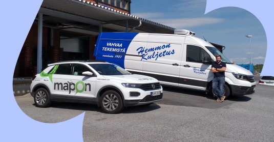 A Mapon car next to a Hemmon Kuljetus cargo van, and the company's representative leaning against it.