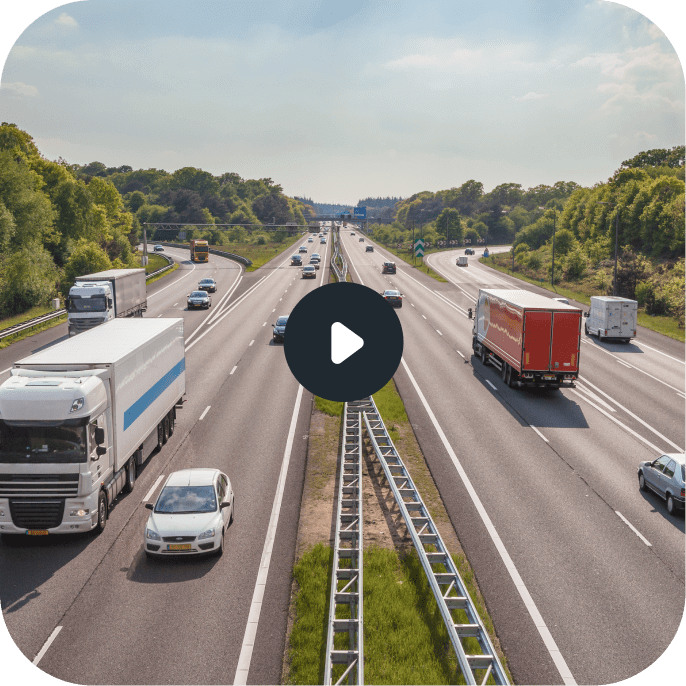 A four lane highway with trucks and passenger cars on both sides.