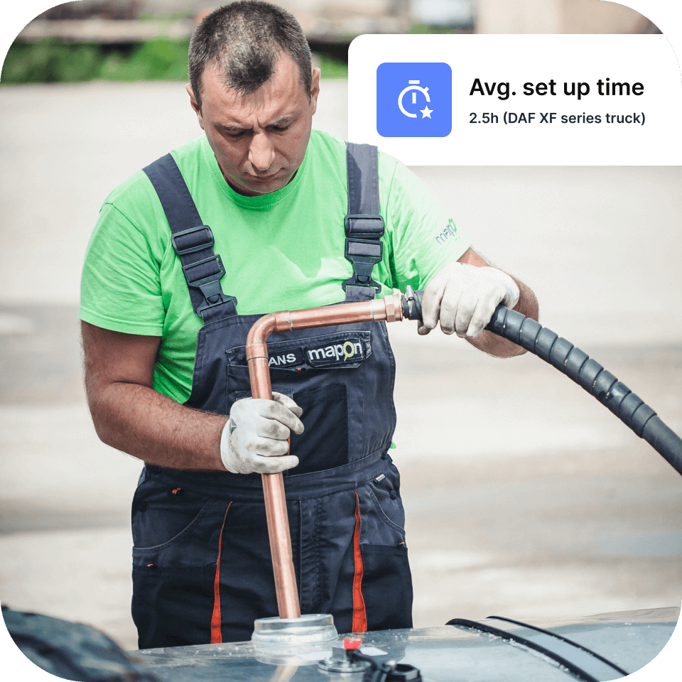 A Mapon technician wearing a green t-shirt, overalls with Mapon logo and white gloves, installing a fuel tracking system.