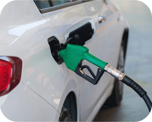 A green fuel nozzle inserted into a petrol tank of a white passenger car.