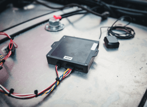 A black telemetry device attached to a large vehicle fuel tank.