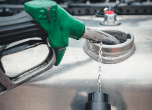Un injecteur de carburant vert inséré dans un grand réservoir d'essence de véhicule sur lequel est installé un capteur de consommation de carburant.