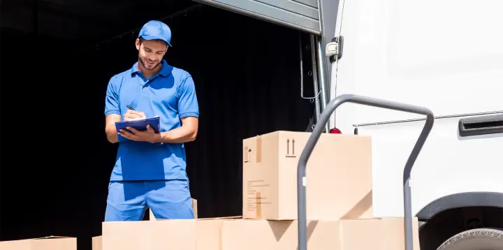 Fleet management for courier services – a delivery driver loads parcels into a white van for last-mile logistics.