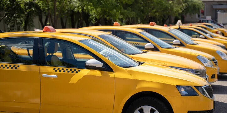 Taxi fleet management – multiple yellow taxis parked in formation, ready for dispatch in an urban setting.
