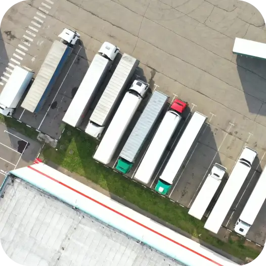 Aerial view of semi-trucks equipped with a fuel alarm system, parked at a logistics center.