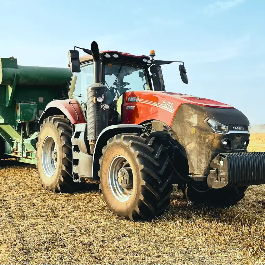 Artis JP’s agricultural tractor with grain trailer parked in a harvested field – tracked and managed using Mapon’s fleet management system.