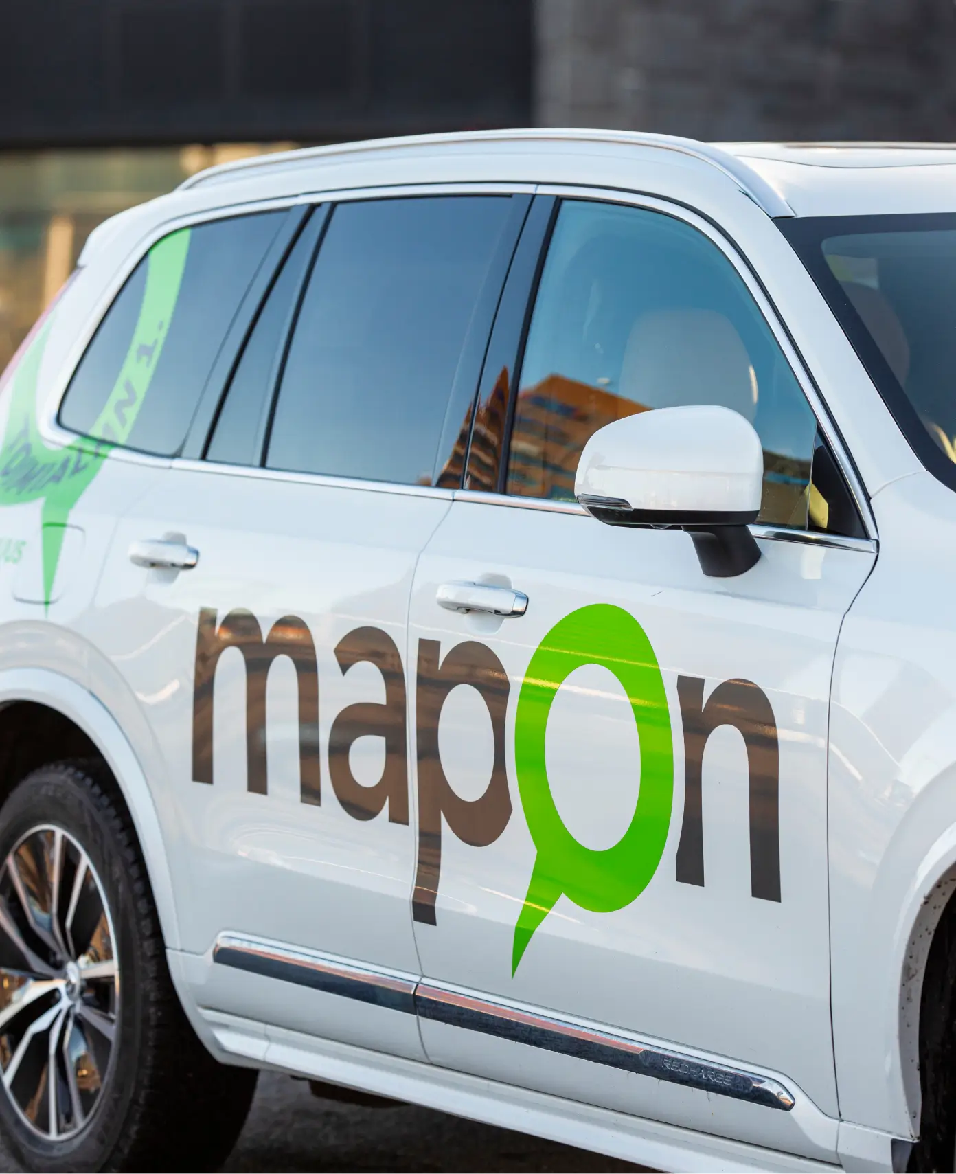 Lateral de un automóvil blanco de pasajeros con un gran logotipo de Mapon.