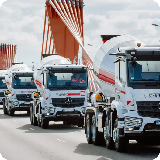 A column of three white cement mixer trucks with Schwenk logos.