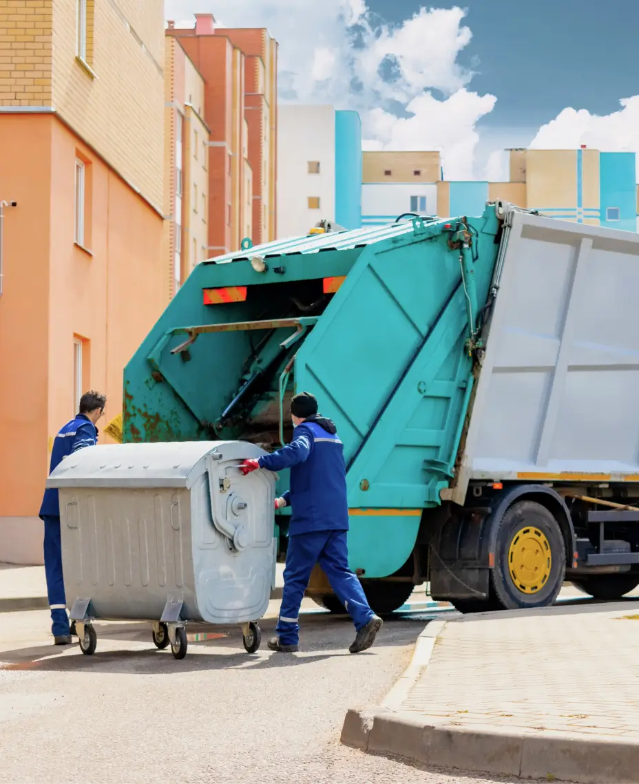Waste collection crew rolling a bin to a garbage truck in a residential area, a daily operation captured by fleet monitoring for waste management.