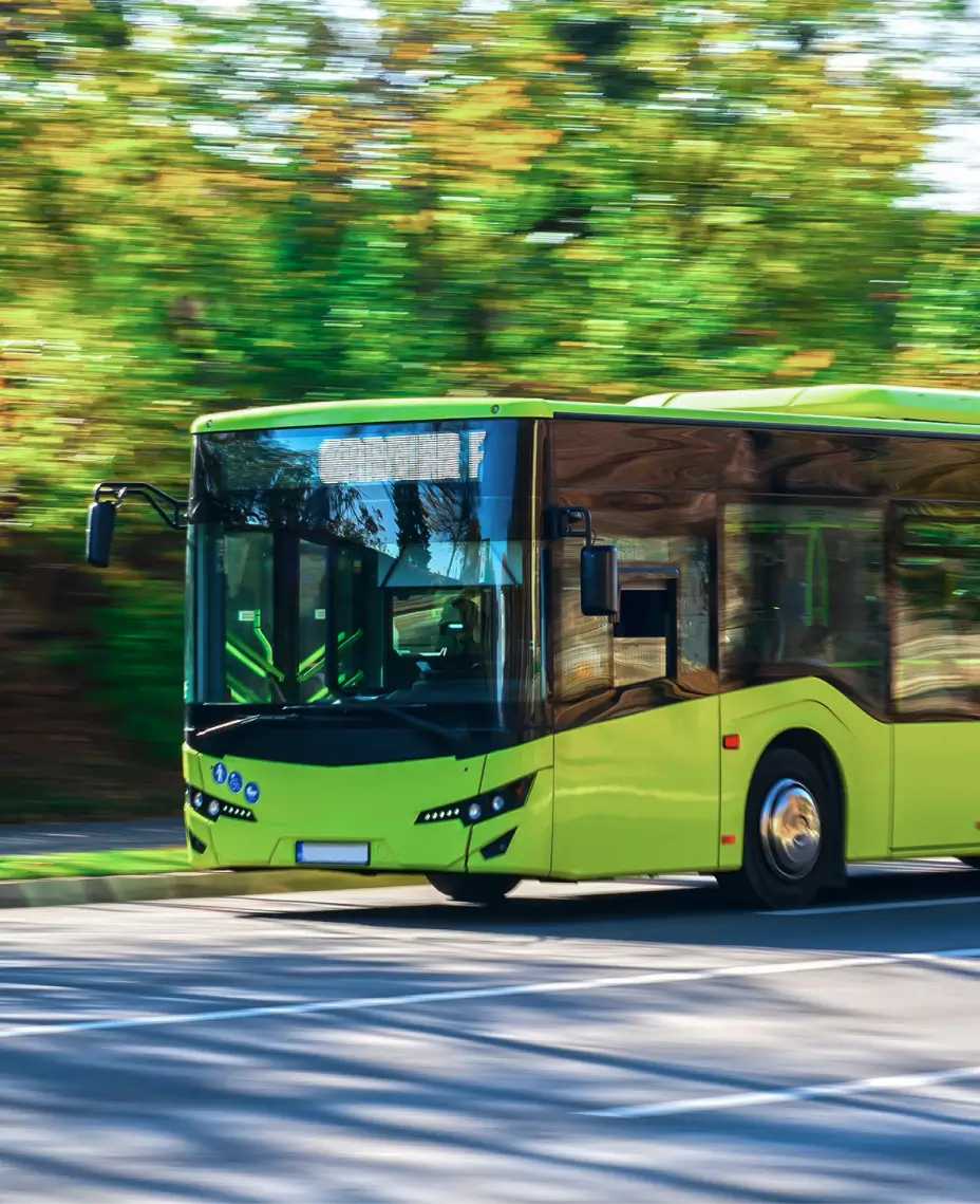 Zaļš autobuss, braucot pa ielu, ar izplūdušu fonu.