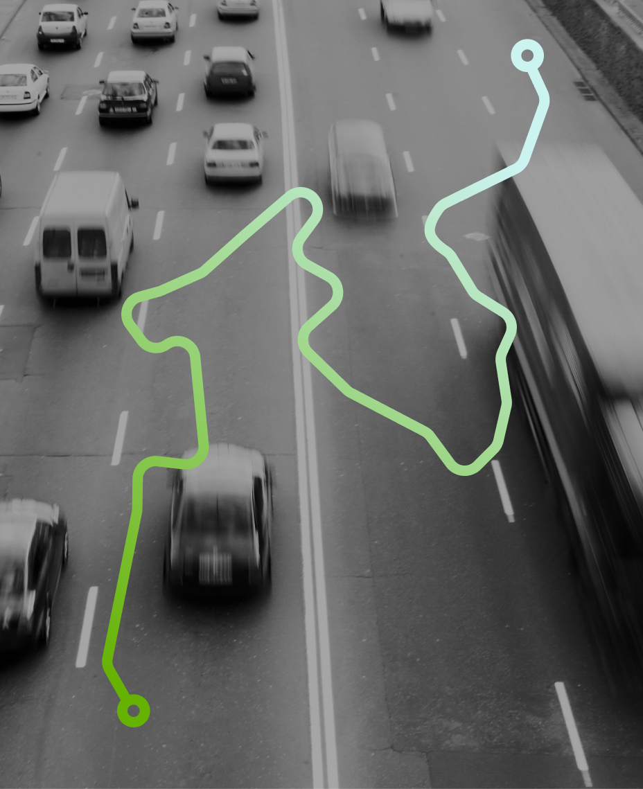 Black and white picture of cars on a road with a drawing of a green route over it.
