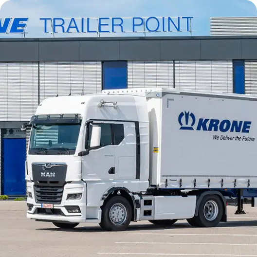 Білий вантажівка з білим причепом KRONE припаркований перед приміщенням KRONE.