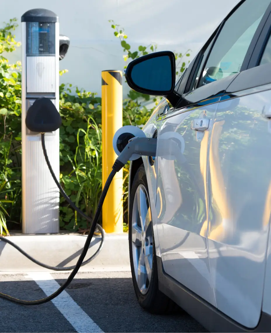 Electric vehicle charging at a public charging station on a sunny day.
