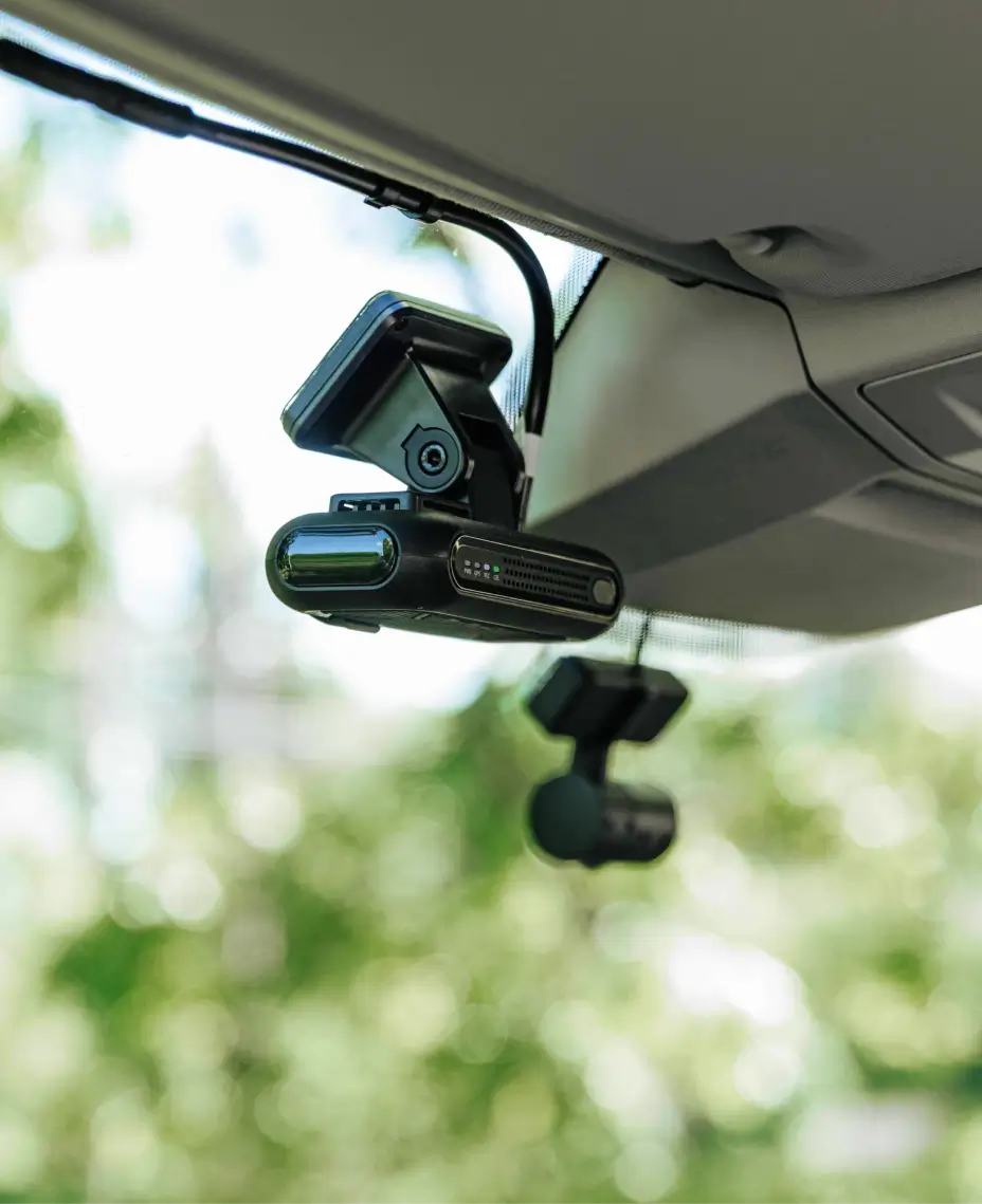 Vehicle interior showing a dual dash camera system installed on the windshield for fleet monitoring.