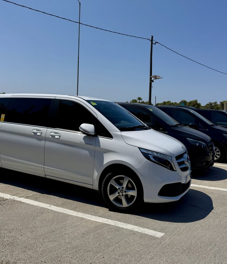 Baltas un melnas minibus automašīnas novietotas stāvlaukumā.