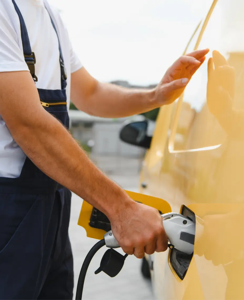 Lähivõte inimesest, kes ühendab laadimiskaablit elektriautoga laadimisjaamas õues.