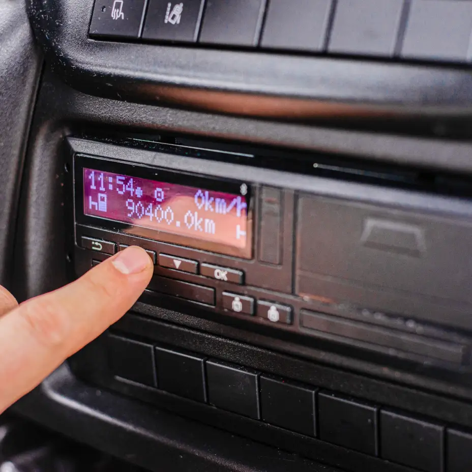 A person pressing a button on a tachograph.
