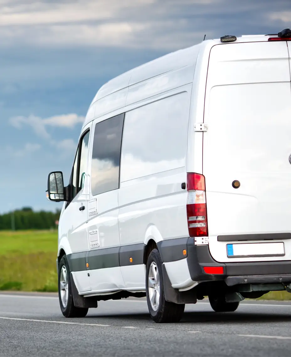 Balts vieglais komerctransports brauc pa ceļu.