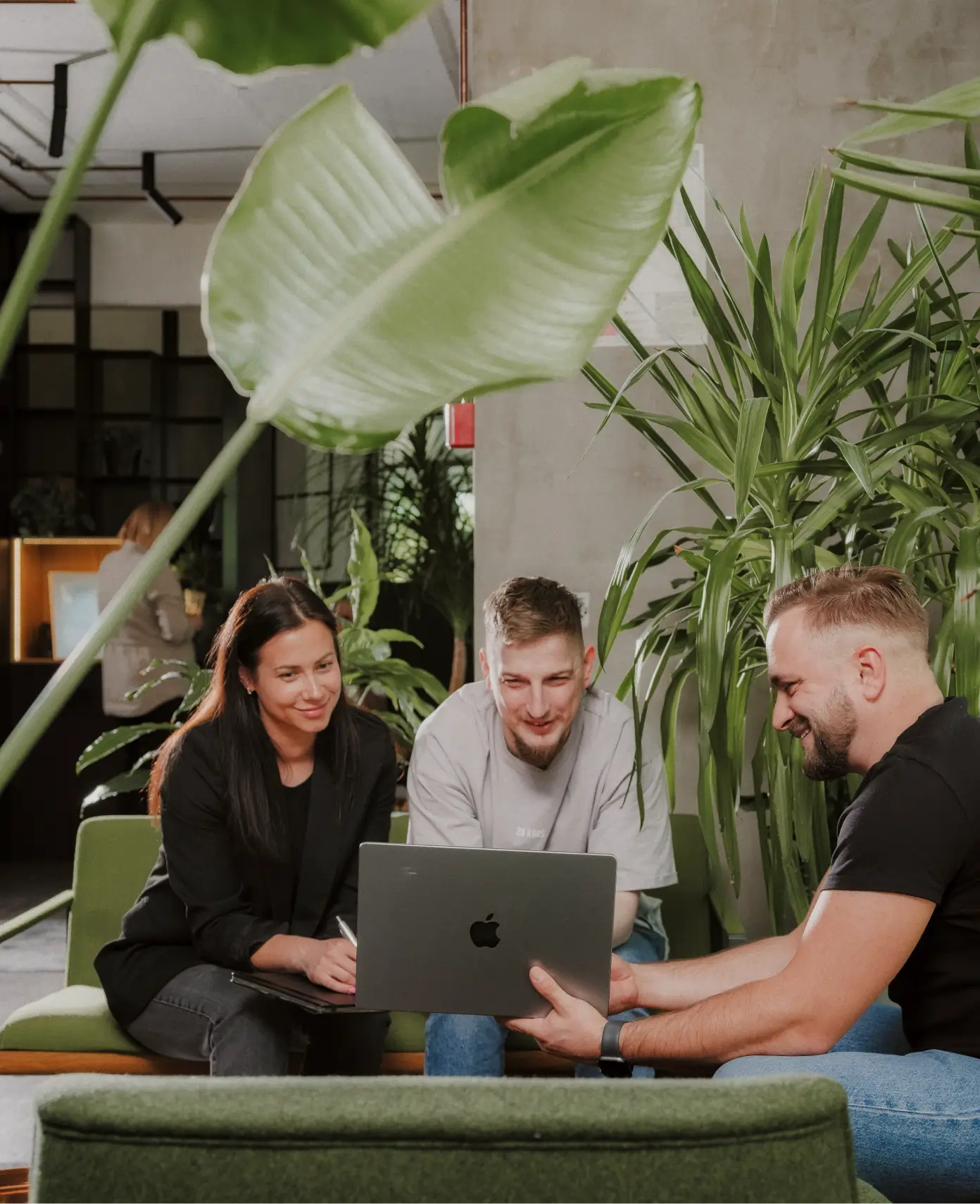 Tre personer diskuterer Mapon flådestyringsløsninger i et kontormiljø.